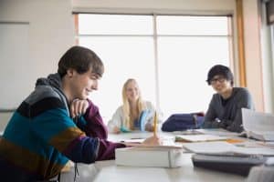 Drie leerlingen zitten lachend aan een tafel tijdens de ideale les.