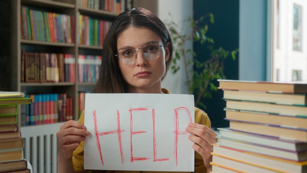 Lerares met bordje in handen waar help op staat