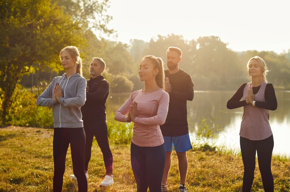 5 mensen bezig met een yoga oefening in de natuur