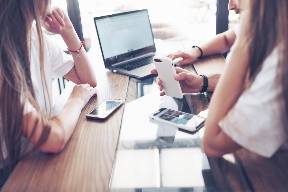mensen overleggen aan tafel met telefoons en laptop erbij