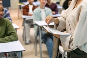 Een docent deelt proefexamens uit in de klas
