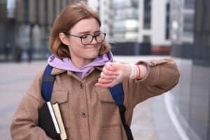 Een leerling kijkt met een moeilijk gezicht naar haar horloge