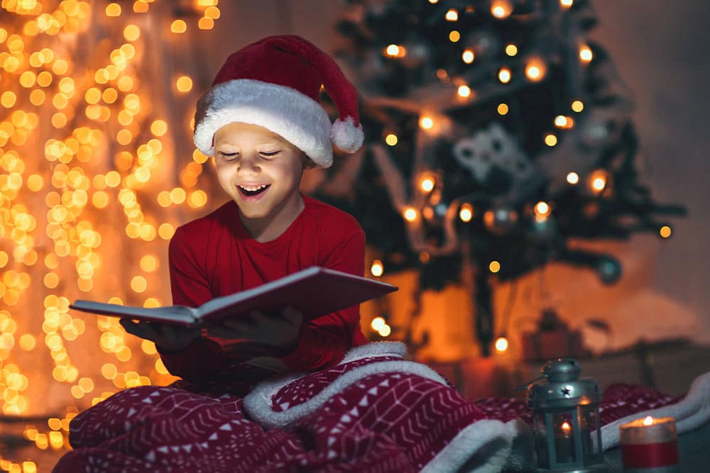 Een kind met een kerstmuts op dat een boek leest