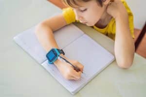 jongetje met een smartwatch aan het schrijven