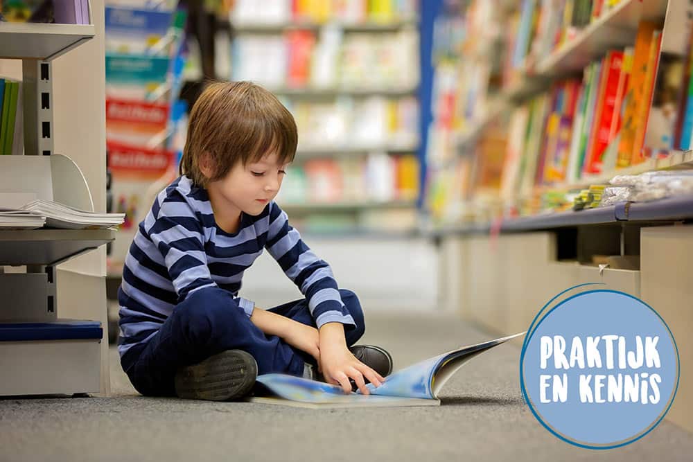 Een kind dat zit te lezen in het gangpad van een bibliotheek