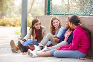 Vier leerlingen praten met elkaar tijdens de pauze met behulp van het smartphoneverbod