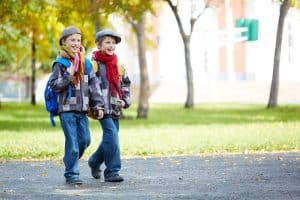 Een tweeling die lachend naar school loopt