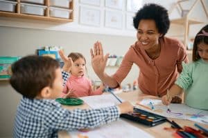 Een lachende leerkracht geeft kind een high five