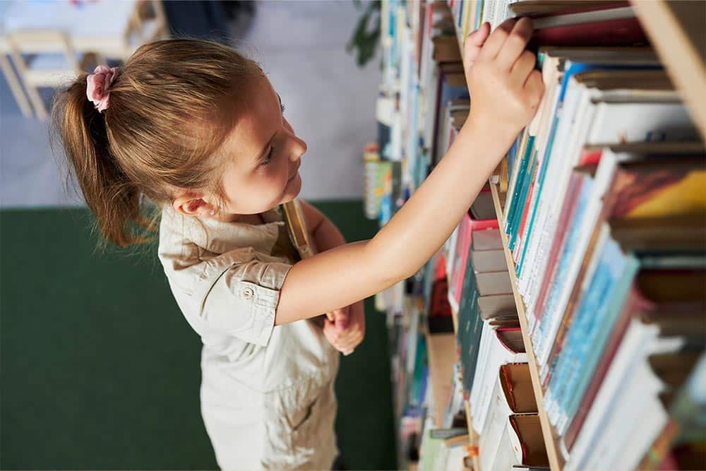 Een kind zoekt een leesboek uit in de bibliotheek