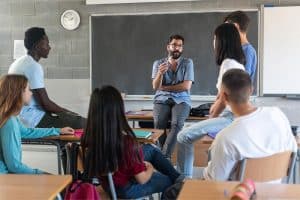 Een docent kletst informeel met zijn leerlingen in een klaslokaal