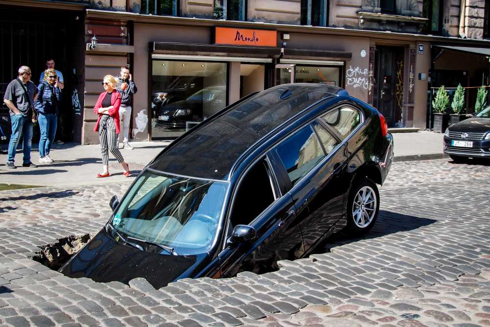 Auto zakt in gat in de weg