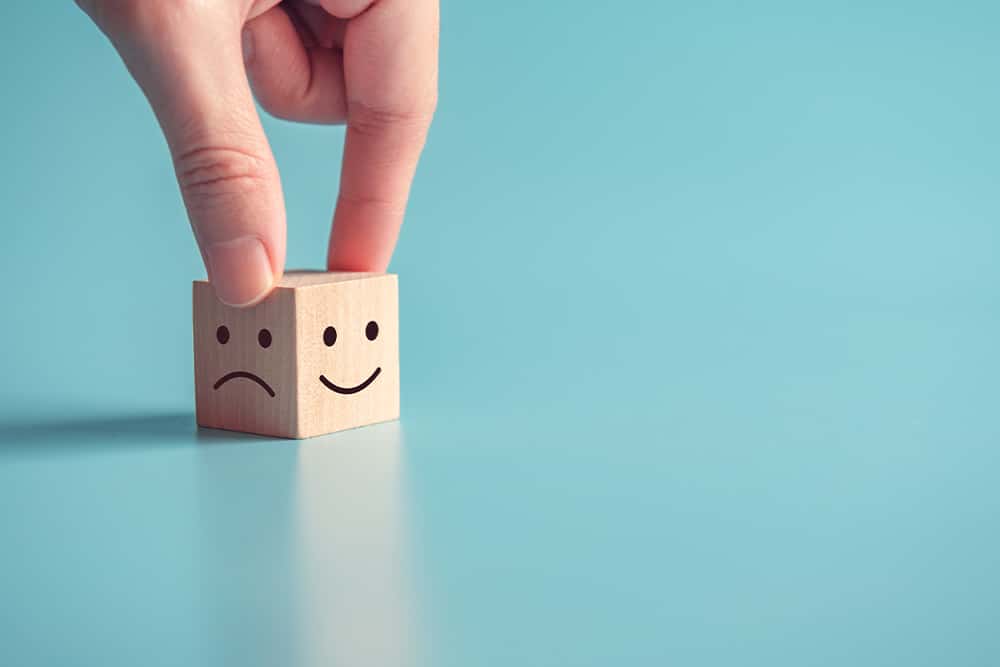 Een kubus met een lachend gezichtje en een verdrietig gezichtje