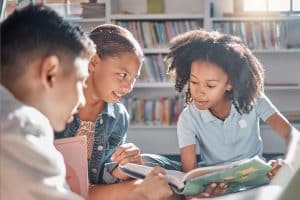 Drie kinderen lezen een boek en overleggen