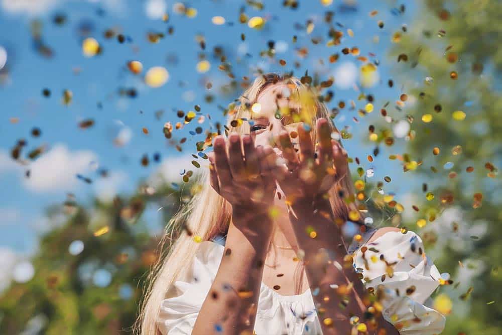Een leerkracht blaast gouden confetti van haar handen om de gouden weken te vieren