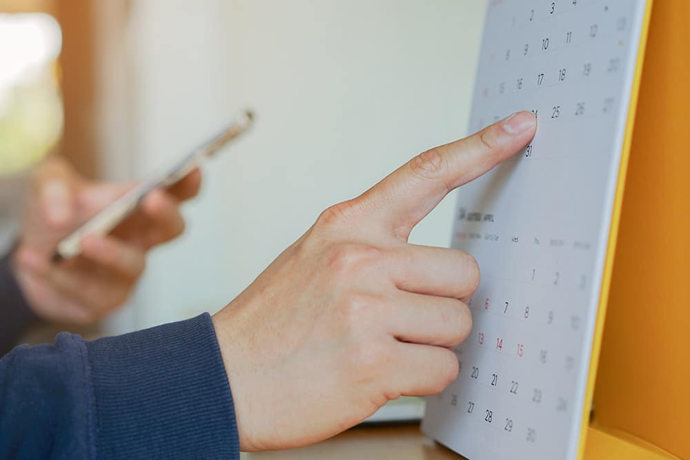 Een leerkracht wijst met zijn vinger naar de kalender voor het bijhouden van de flexibele onderwijstijd