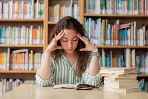 Een vermoeide tiener met prestatiedruk boven haar studieboeken