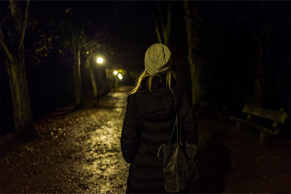 Een vrouw loopt in het donker alleen op straat