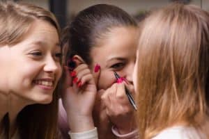 Drie meiden werken hun make-up bij voor de schoolfoto