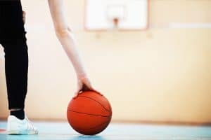 Leerkracht die een basketbal vastpakt in de gymzaal