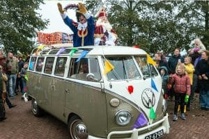 Sint en Piet komen in een versierd busje aan op school