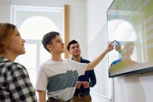 Twee leerlingen en een leerkracht werken met het digibord in de klas