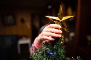 Een kind zet de piek op een kerstboom tijdens het kerstfeest op school
