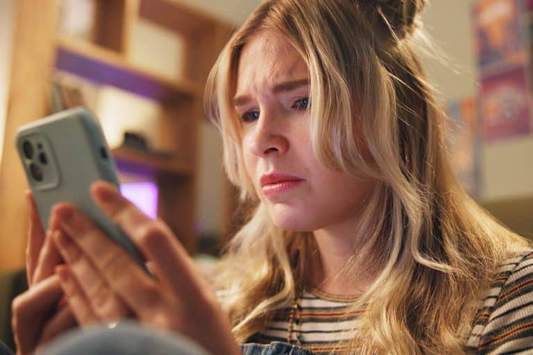 Een mbo-student die door online pesten verdrietig op haar telefoon kijkt