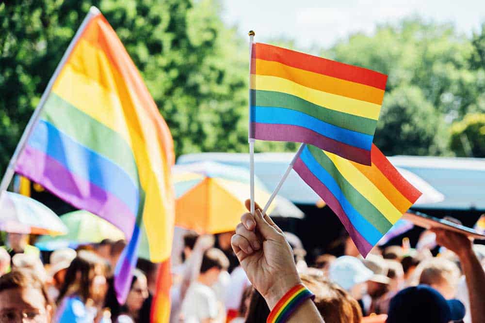 Jongeren zwaaien met regenboogvlaggen
