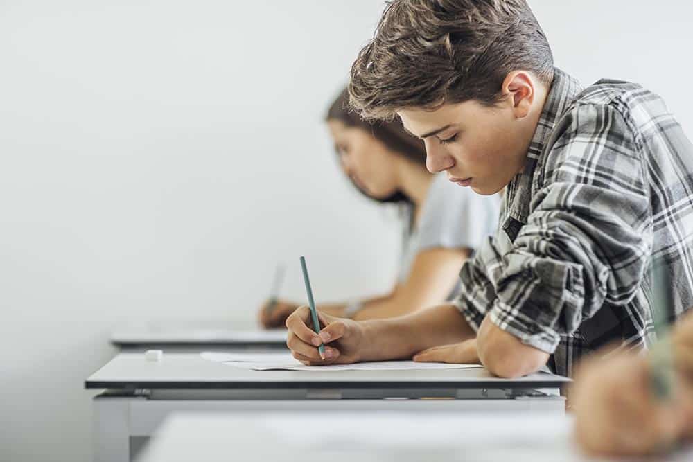 Een schrijvende jongen in de klas