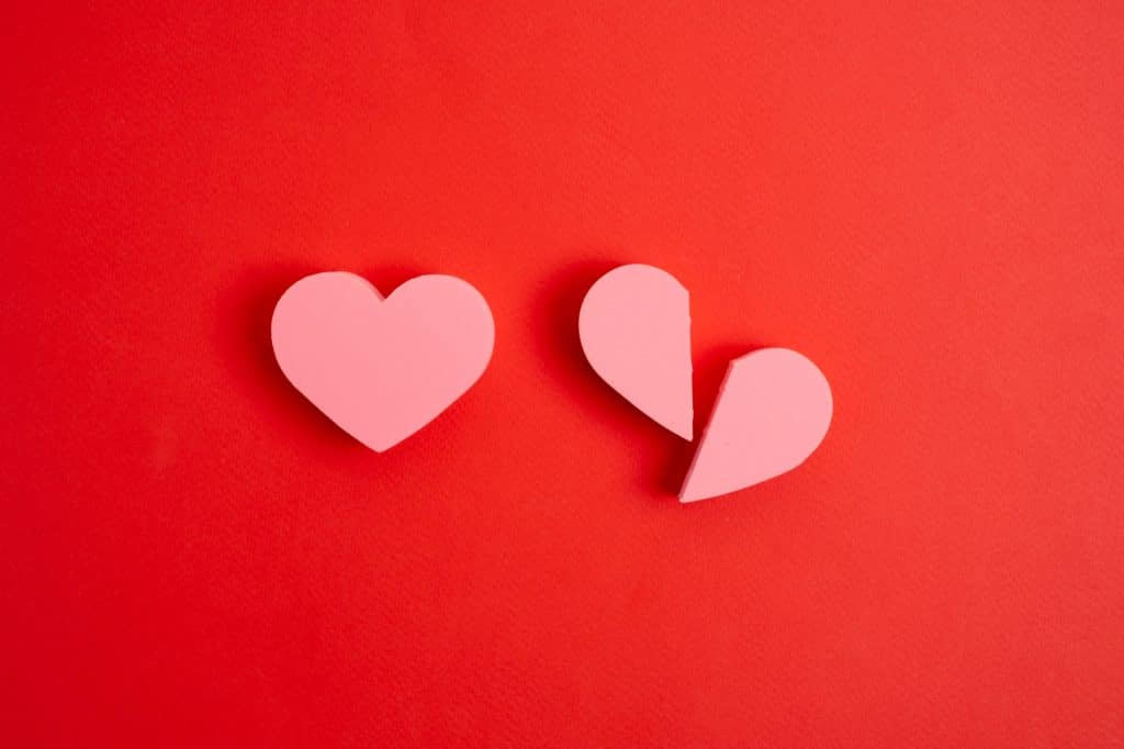 Broken and whole hearts on red background.