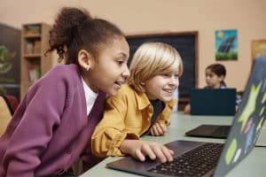 Twee kinderen werken achter een laptop op school
