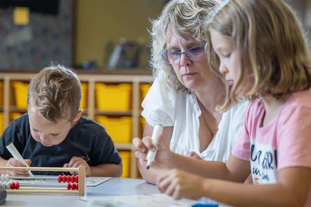 Een leerkracht observeert twee kinderen tijdens de rekenles