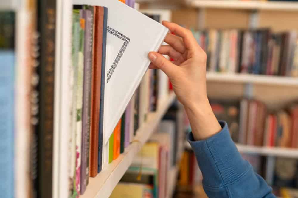 Een leerling pakt een boek uit de boekenkast van de schoolbibliotheek
