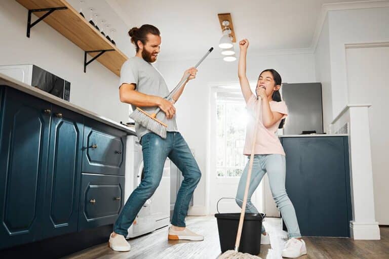 Een vader speelt luchtgitaar op een bezem