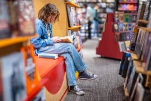 Een tiener leest een boek in de mediatheek op school