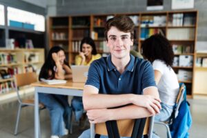 Een jongen kijkt met een glimlach in de camera met op de achtergrond zijn klasgenoten