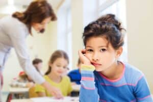 Een meisje kijkt verveelt voor zich uit in de klas