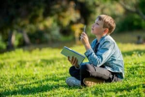 Een kind zit buiten te dichten