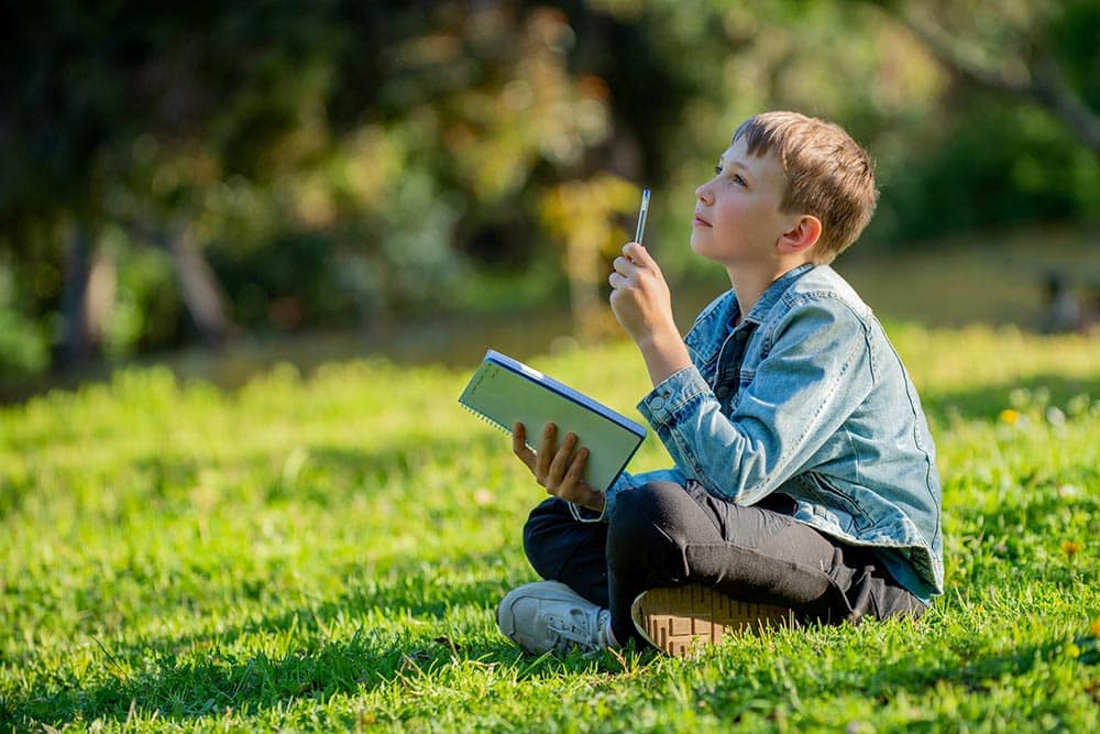 Een kind zit buiten te dichten