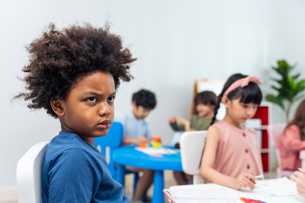 Een kind kijkt boos in de klas