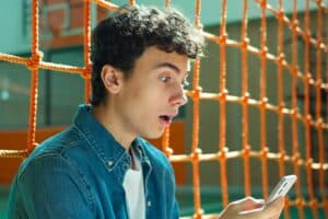 Een leerling kijkt verbaasd op zijn telefoon