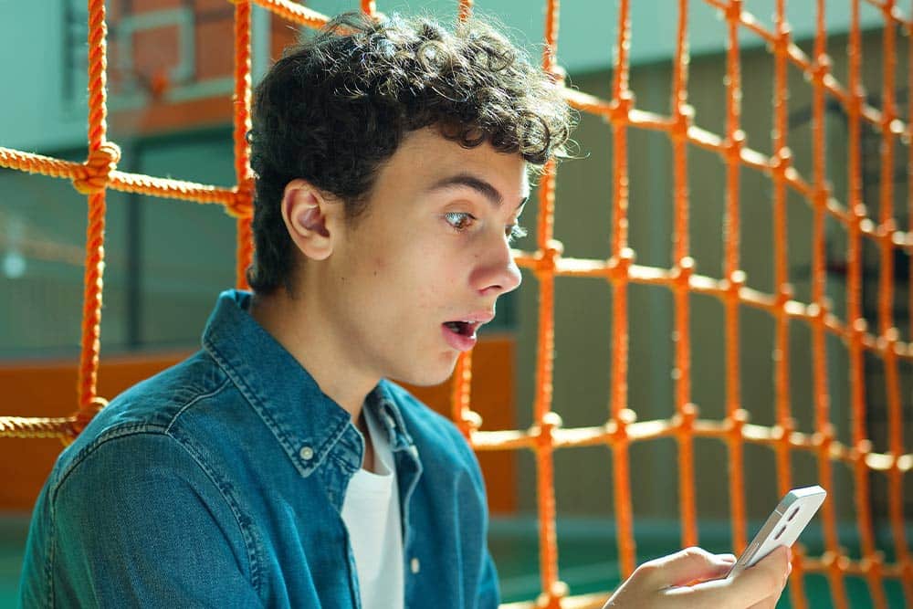 Een leerling kijkt verbaasd op zijn telefoon