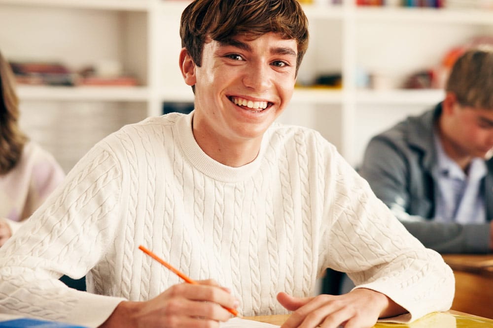 Een leerling maakt gebruik van passend examineren en kijkt met een glimlach in de camera