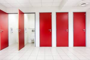 Vijf schooltoiletten op een rij, twee deuren staan open, er zijn schone toiletten te zien