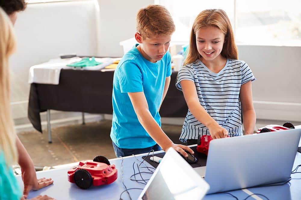 Twee leerlingen kijken naar een computer tijdens de programmeerclub op school
