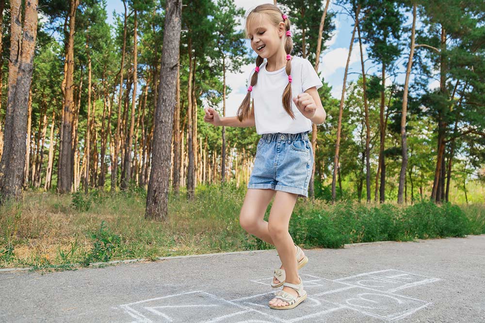 Een meisje springt op in hinkelpad als een zomerse energizer