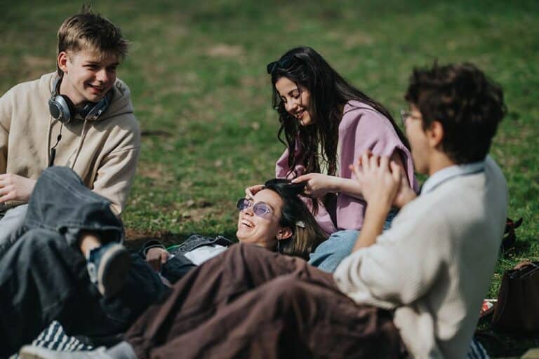 Studenten liggen ontspannen in het gras naast de school