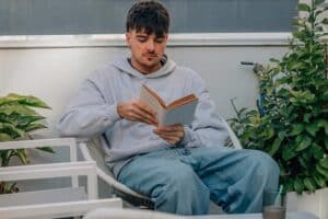 Een jongeman zit te lezen in de tuin