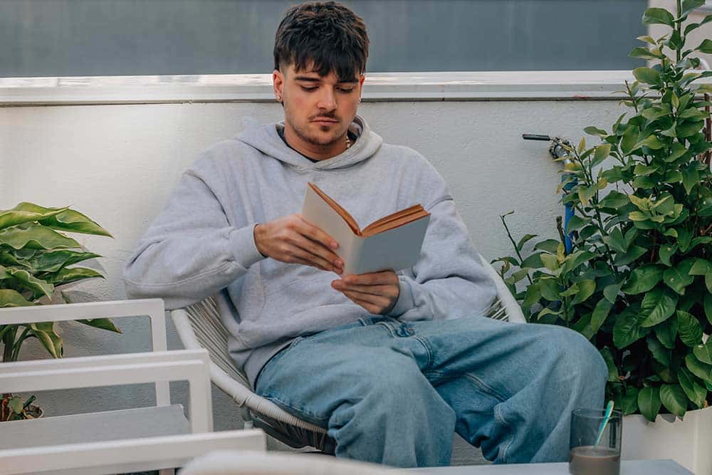 Een jongeman zit te lezen in de tuin