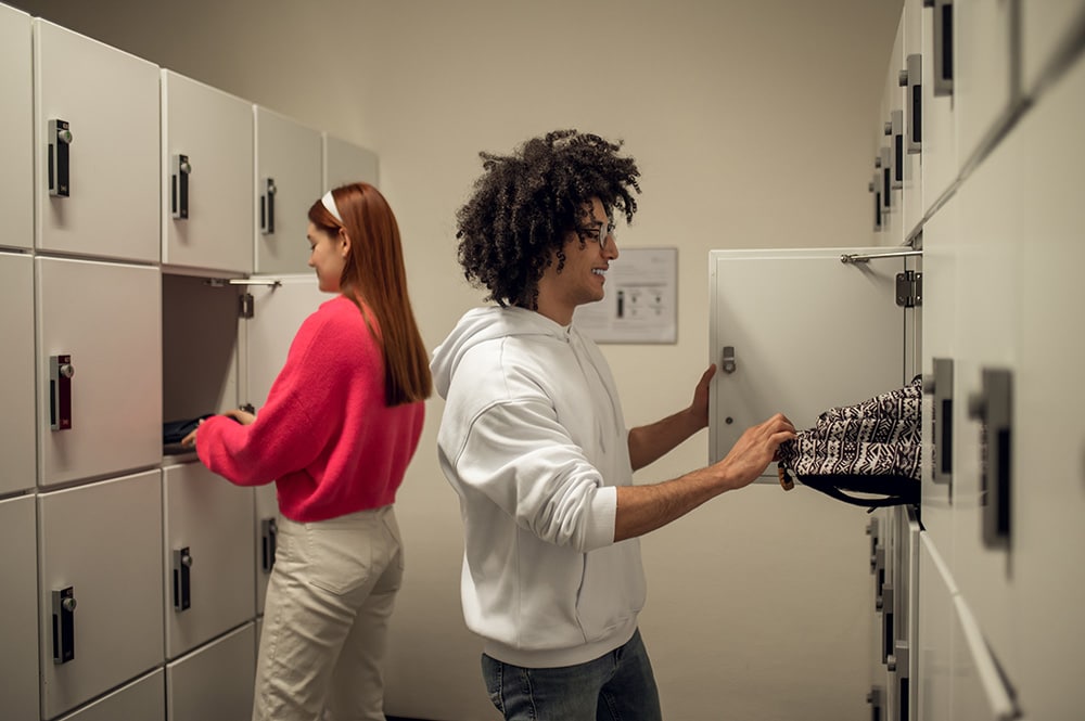 Twee studenten praten met elkaar bij de kluisjes in een schoolgang.